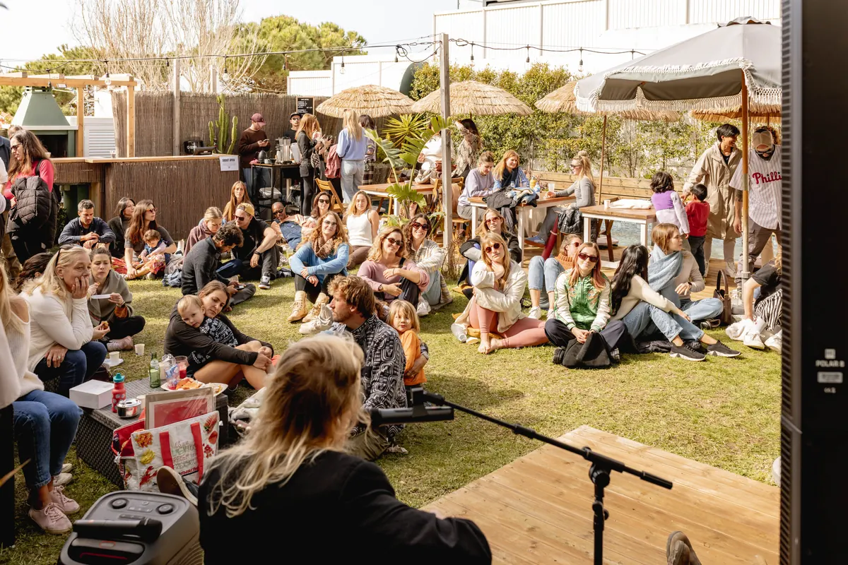 A crowd seated on the grass at an outdoor gathering