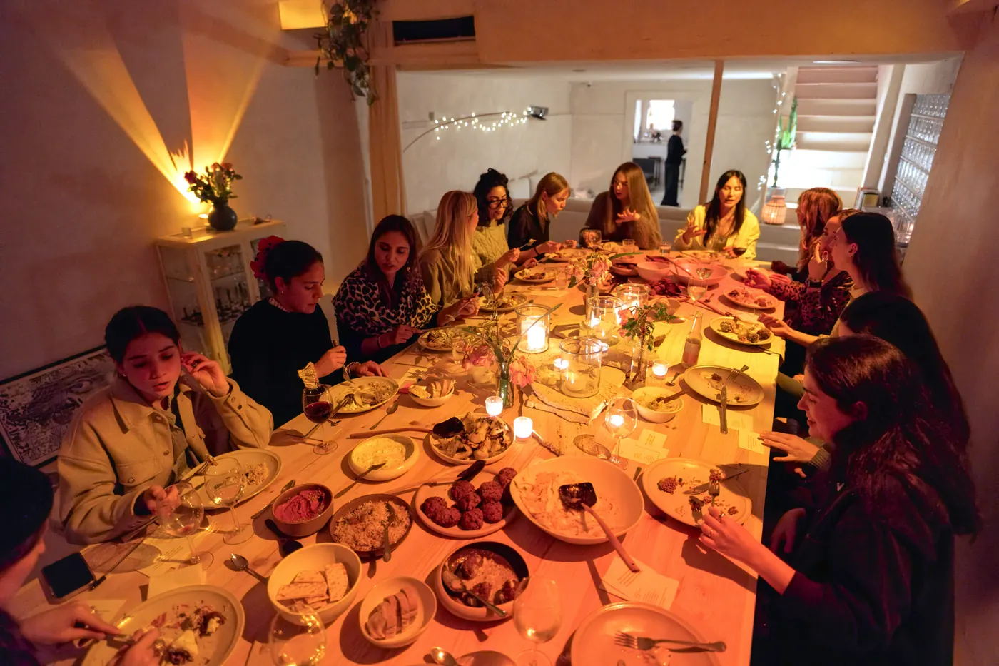 Guests around a long candlelit dinner table