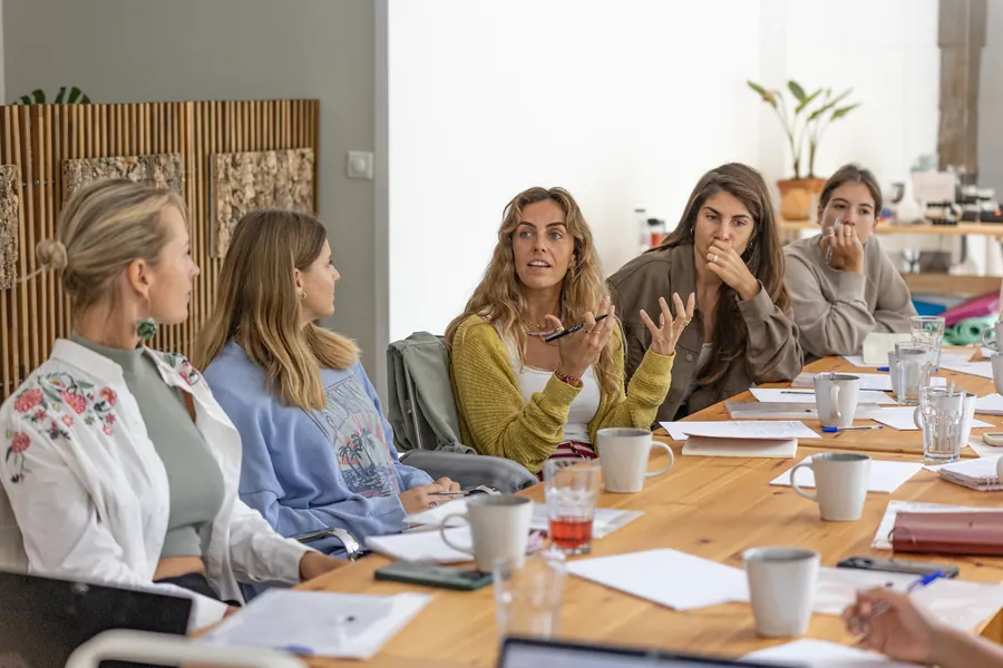 A small group deep in conversation around a workshop table