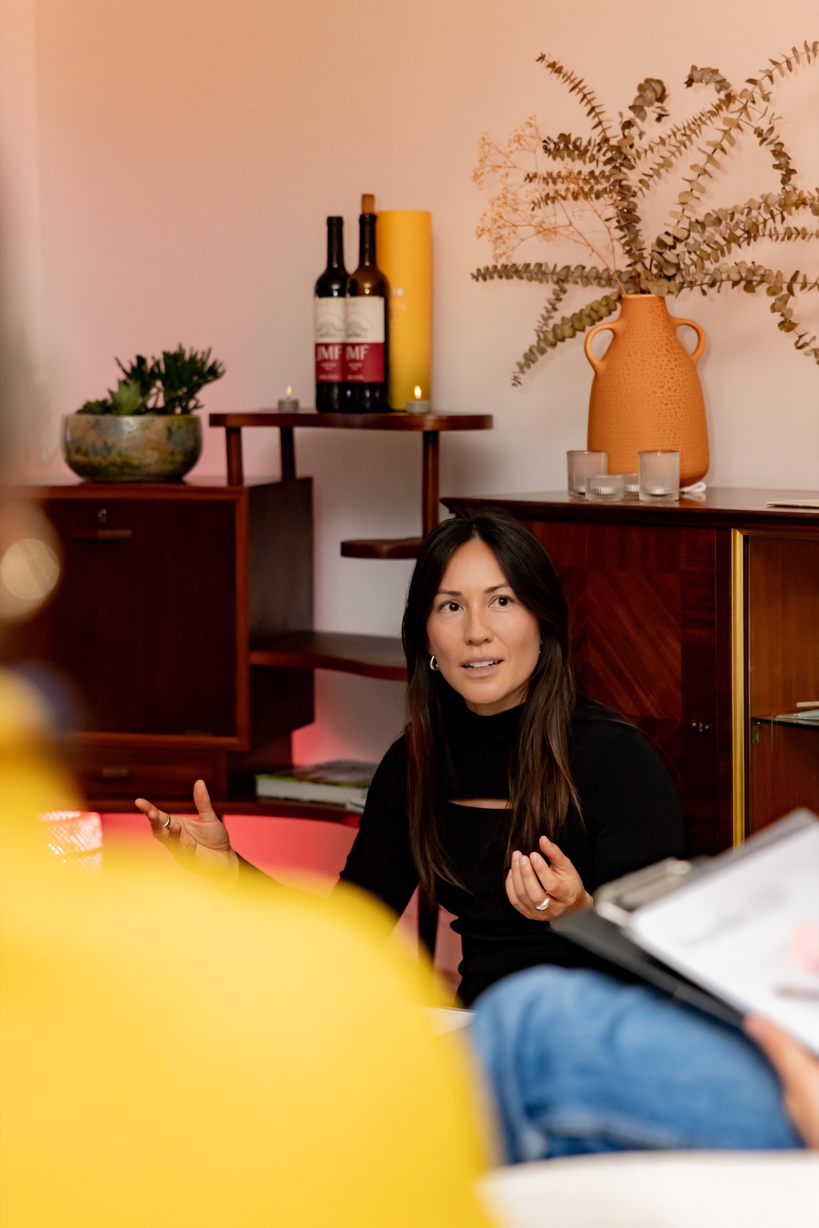 Jennifer Nunez speaking with her hands raised as she talks with a small group in a warmly lit room