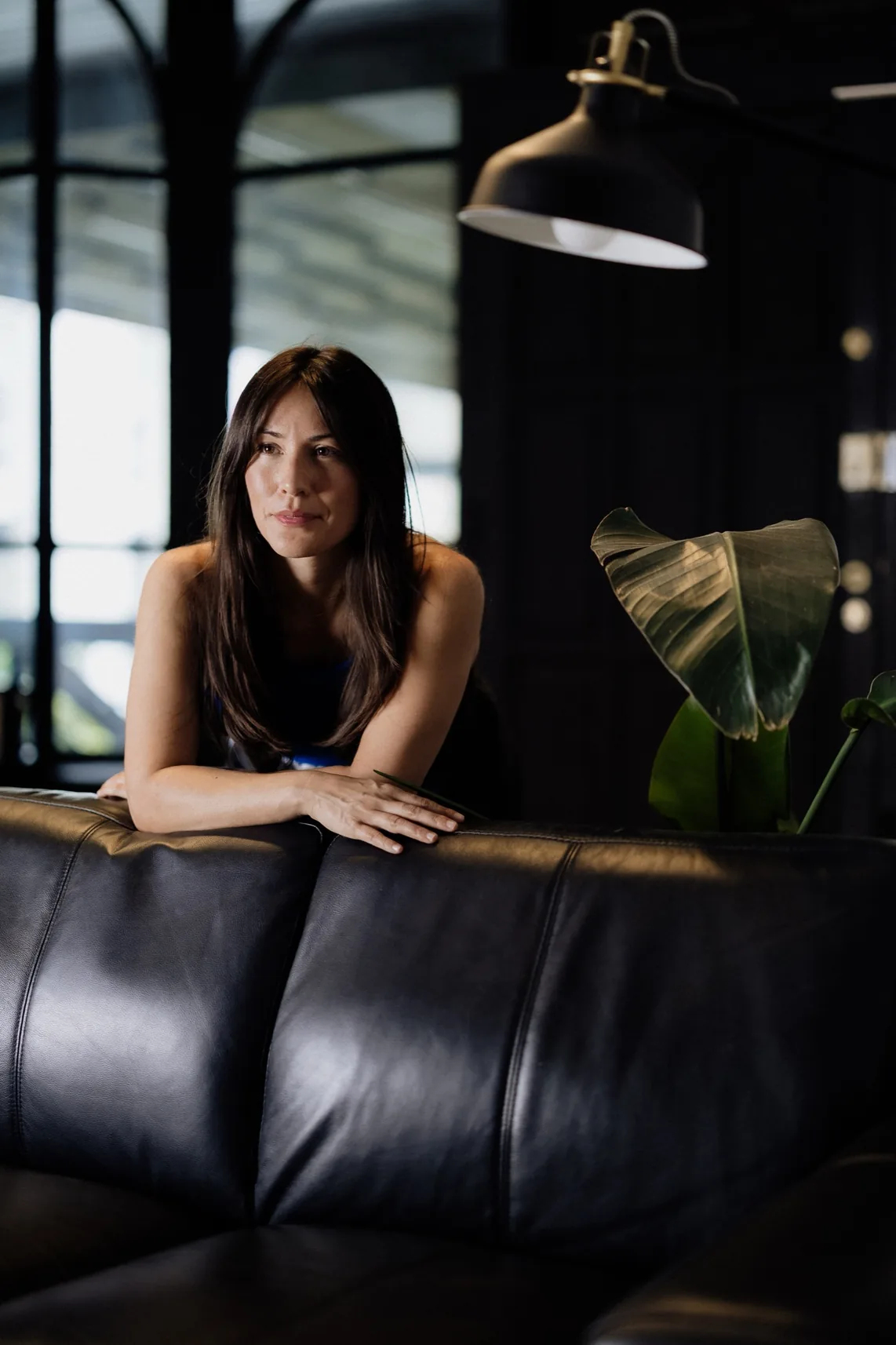 Jennifer Nunez leaning on the back of a leather sofa