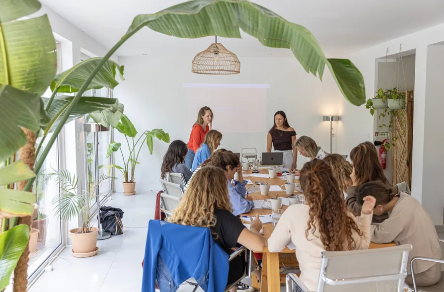 A workshop underway around a long table in a bright, plant-filled room